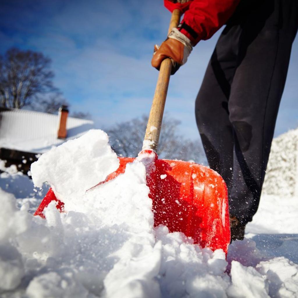 Человек чистит снег лопатой