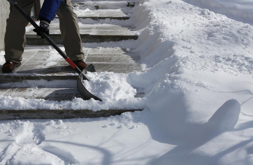 Человек чистит снег на ступеньках