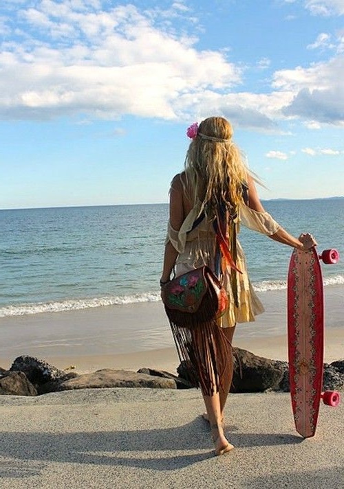 Девушка хиппи на пляже, одета в короткое платьице, на плче сумка с бахромой