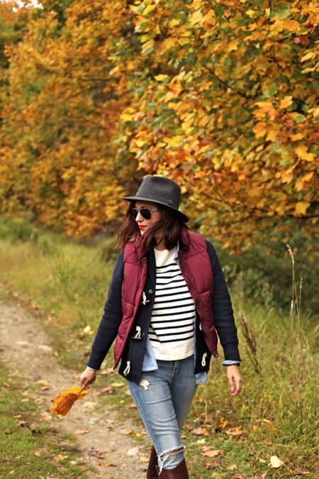 Девушка в рваных джинсах, белом свитшоте, бордовая жилетка и шляпа