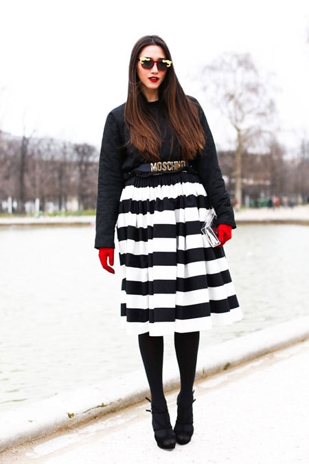 Модель в полосатой черно-белой юбке, черная кофта и красные перчатки