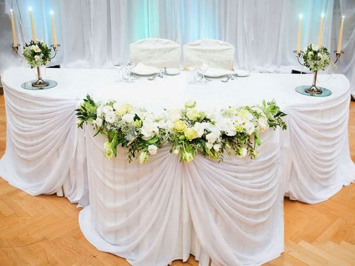 Свадебный стол с белой декорирующей тканью и подсвечниками